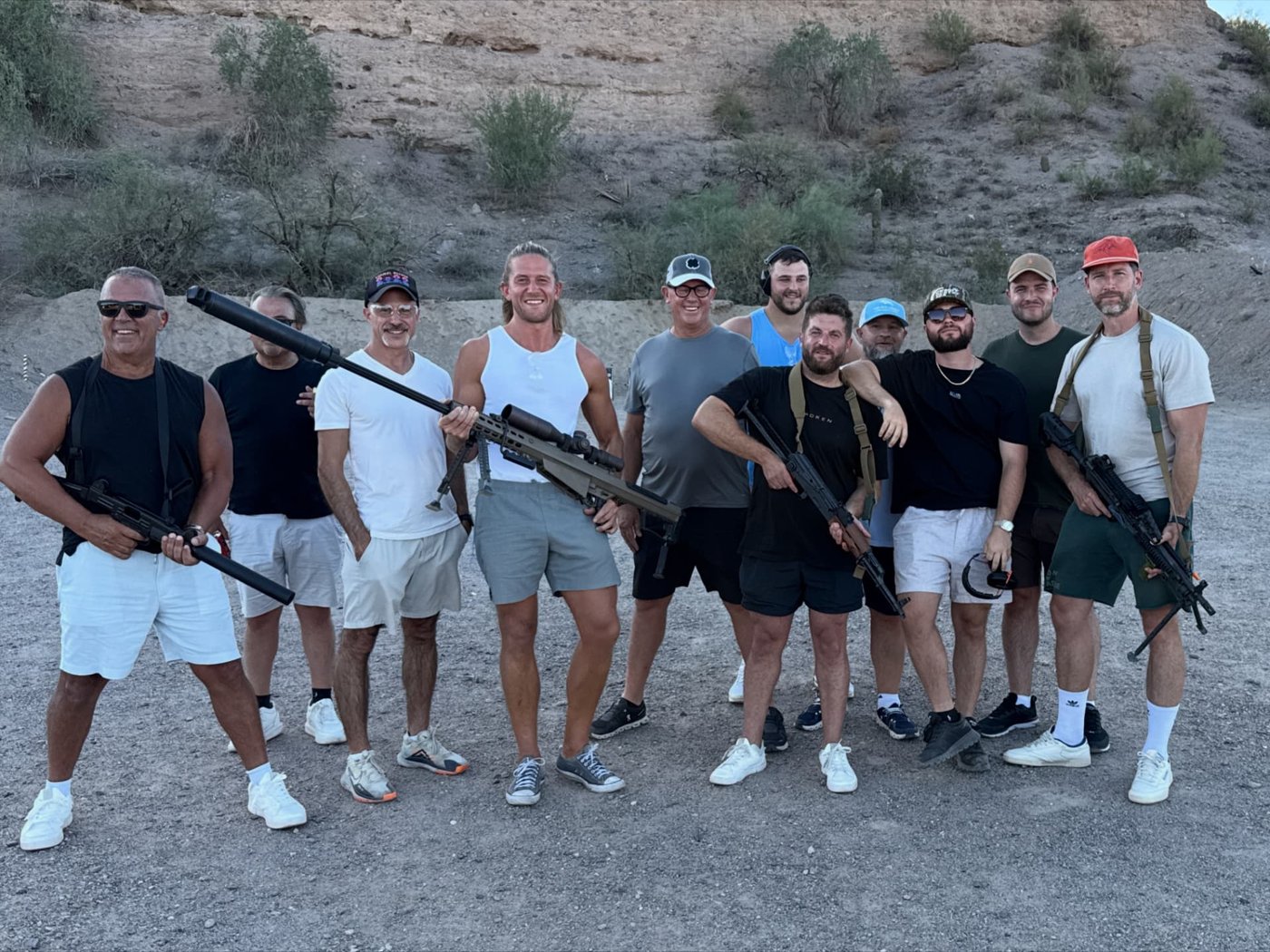 A group of guests and instructors posing outdoors after a supervised shooting experience