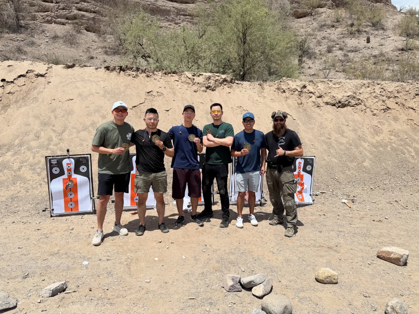 Guests and an instructor standing with completed targets after an outdoor shooting session